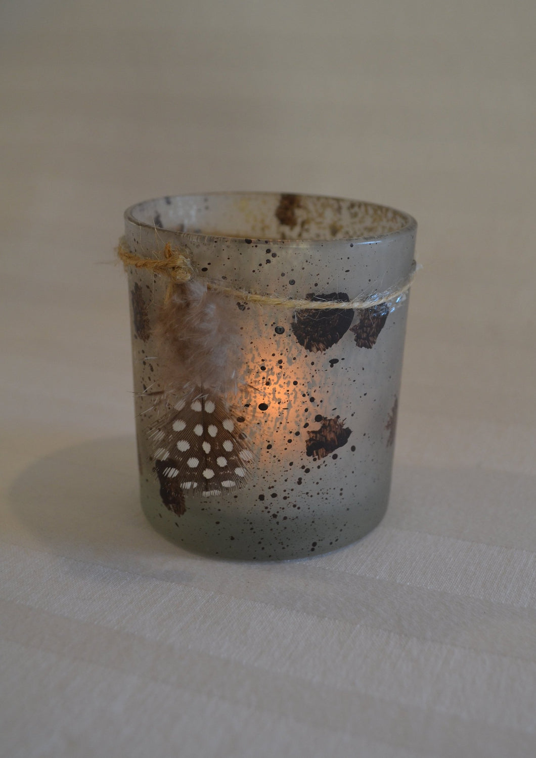 Speckled tea light candle with feather